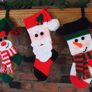 May include: Three crocheted Christmas stockings hanging on a brick fireplace mantel. The stockings are decorated with Santa, a snowman, and a reindeer.