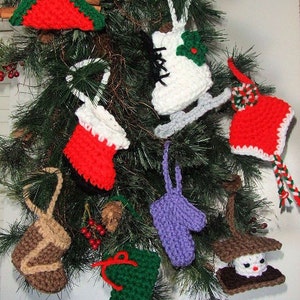May include: A collection of crocheted Christmas ornaments, including a stocking, a boot, a mitten, a skate, a gnome, and a snowman. The ornaments are all different colors and are hanging on a Christmas tree.