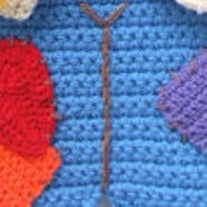 May include: A blue crocheted scarecrow costume with red, orange, and purple patches. The scarecrow has a straw hat and a brown crocheted belt.