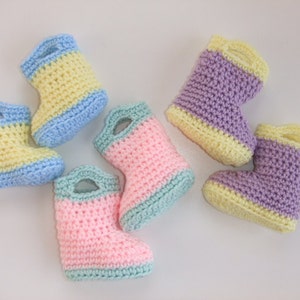 Puede incluir: Seis pares de botines de bebé tejidos a crochet en rosa, morado, azul y amarillo. Los botines tienen un puño doblado y un ribete de color contrastante.