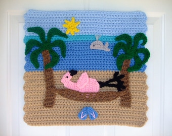 Puede incluir: Un tapiz de pared tejido a crochet que representa una escena de playa con un flamenco rosa en una hamaca, palmeras, un cielo azul con un sol amarillo y una ballena en el océano. La playa es marrón, el océano es azul, el cielo es azul claro, el sol es amarillo, las palmeras son verdes, el flamenco es rosa y la ballena es gris.