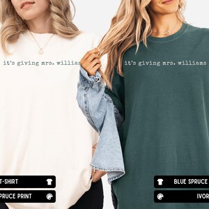 K&ouml;nnte beinhalten: Zwei T-Shirts mit Rundhalsausschnitt, eines in Elfenbein und eines in Blaufichte, beide mit dem schwarzen Text "it's giving mrs. williams" im Schreibmaschinenstil auf der Brust. Die T-Shirts haben kurze &Auml;rmel und eine lockere Passform.