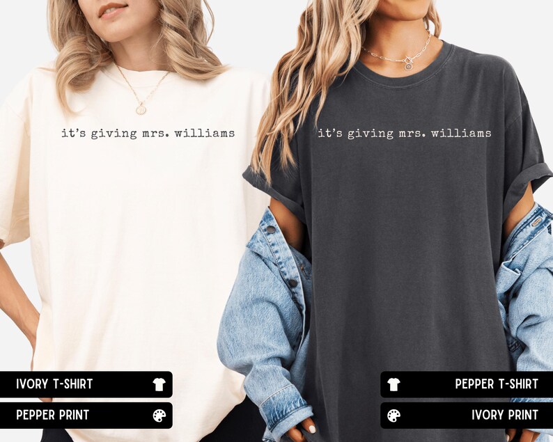 K&ouml;nnte beinhalten: Zwei kurz&auml;rmelige T-Shirts mit Rundhalsausschnitt, eines in Elfenbein und eines in Pfeffergrau, jeweils mit dem schwarzen Schriftzug 'it's giving mrs. williams' in Schreibmaschinen-Optik auf der Brust, in einer lockeren Passform.