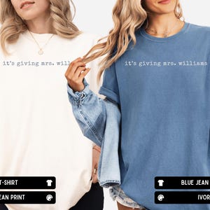 K&ouml;nnte beinhalten: Zwei kurz&auml;rmelige T-Shirts mit Rundhalsausschnitt, eines in Elfenbein und eines in Jeansblau, jeweils mit dem wei&szlig;en Schriftzug 'it's giving mrs. williams' auf der Brust in Schreibmaschinen-Optik. Die Shirts haben eine lockere Passform.