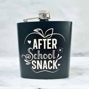 May include: Black flask with a silver top and a white graphic of an apple with the text "AFTER SCHOOL SNACK".