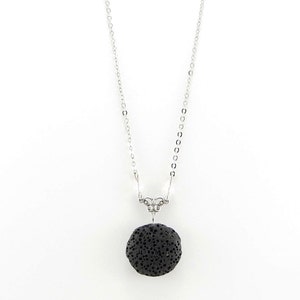May include: A silver chain necklace with a black lava rock pendant.