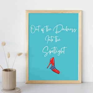 Könnte beinhalten: Ein türkisfarbener gerahmter Druck mit dem Text "Out of the Darkness Into the Spotlight" in weißer Kursivschrift. Unter dem Text ist ein roter High-Heel-Schuh mit einer blau-weiß gestreiften Schleife abgebildet.