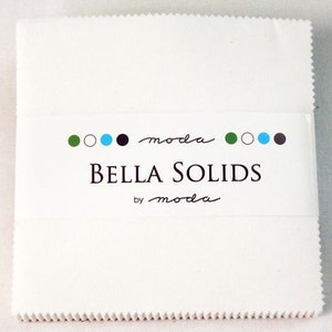 May include: White fabric square with a label that reads "Bella Solids by moda" with a green, white, blue, and black circle design.