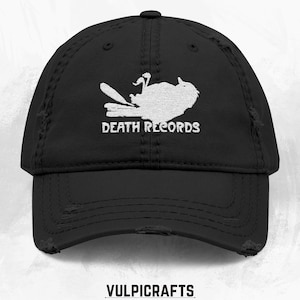 May include: Black distressed baseball cap with white graphic and text "DEATH RECORDS". The cap features a curved brim and a distressed finish, with a small logo at the bottom.