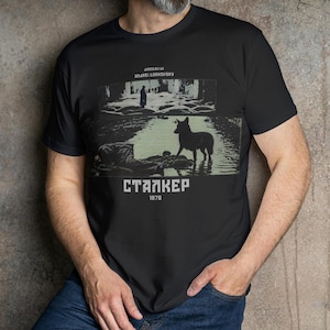 May include: Black t-shirt featuring a graphic from the film "Stalker" with a dog in water and the text "STALKER 1979". The design is in shades of green and white.