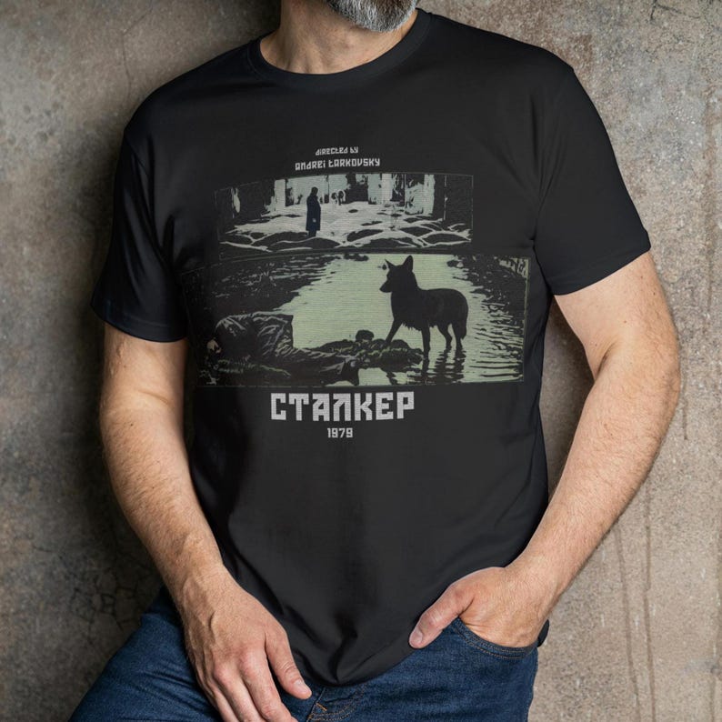 May include: Black t-shirt featuring a graphic from the film "Stalker" with a dog in water and the text "STALKER 1979". The design is in shades of green and white.