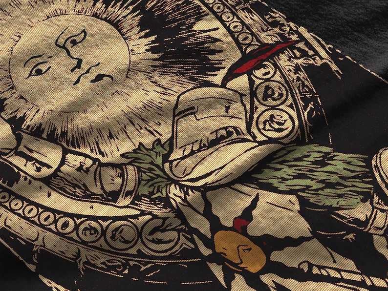 Puede incluir: Una prenda de tela negra con una serigraf&iacute;a en tono dorado que muestra un sol con rostro humano, un caballero con armadura y patrones circulares decorativos. El dise&ntilde;o incluye acentos de follaje verde y un peque&ntilde;o detalle rojo.