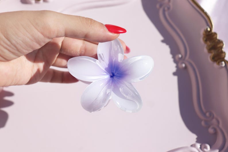 May include: A white and purple glass flower with five petals. The flower is translucent and has a delicate, feminine appearance.