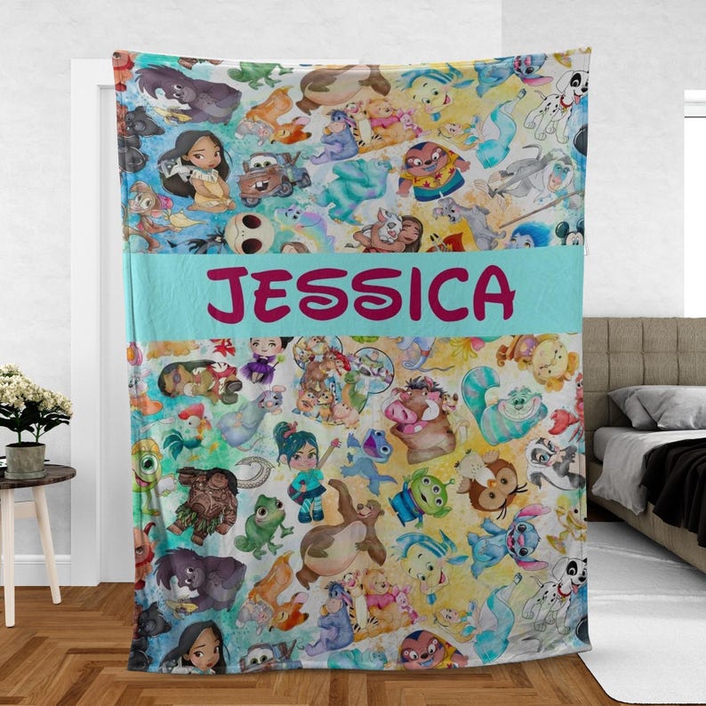 K&ouml;nnte beinhalten: Eine farbenfrohe Decke mit verschiedenen Zeichentrickfiguren im Aquarellstil. Die Decke hat ein hellblaues Band mit dem Namen "JESSICA" in rosa Buchstaben. Die Decke ist eine Mischung aus Gelb, Blau und Wei&szlig;.