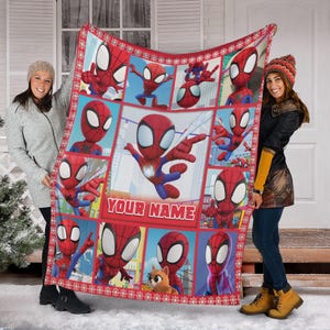 Pu&ograve; includere: Una coperta rossa e blu a tema Spider-Man con un motivo a griglia che presenta varie pose del supereroe. La coperta ha un bordo rosso con dettagli a fiocco di neve e il testo "YOUR NAME".