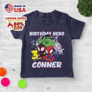 Puede incluir: Una camiseta de manga corta azul marino con un estampado gr&aacute;fico de cinco superh&eacute;roes de dibujos animados, incluidos Hulk, Spider-Man y Black Panther. El texto dice BIRTHDAY HERO, el n&uacute;mero 3 en amarillo y el nombre CONNER en letras blancas.