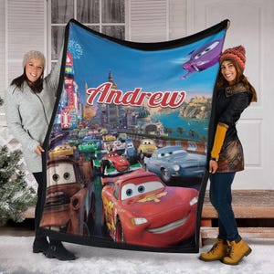 Op de afbeelding: Een zachte deken met een levendige sc&egrave;ne uit de animatiefilm Cars, met de naam "Andrew" in grote rode letters. Het ontwerp bevat Bliksem McQueen en andere personages die racen tegen een stadsachtergrond.