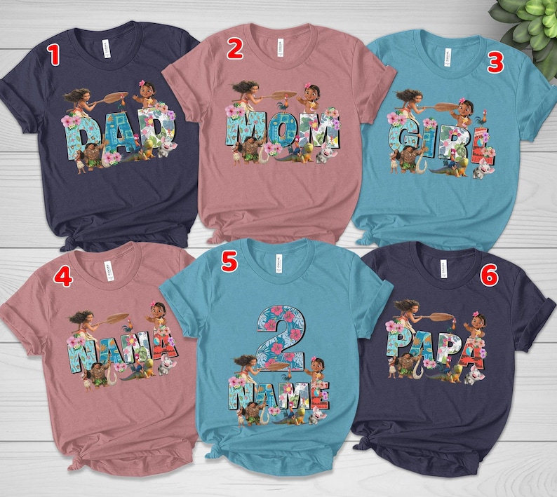 May include: Six short-sleeved crew neck t-shirts in navy, dusty rose, and teal. Each shirt features a graphic print of characters from the movie Moana integrated into large block letters spelling DAD, MOM, GIRL, NANA, 2 NAME, and PAPA.