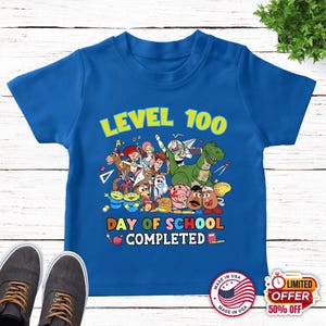 May include: A royal blue short-sleeved t-shirt featuring a colorful graphic of Toy Story characters. The text reads LEVEL 100 DAY OF SCHOOL COMPLETED, surrounded by illustrations of school supplies like pencils, rulers, and an apple.