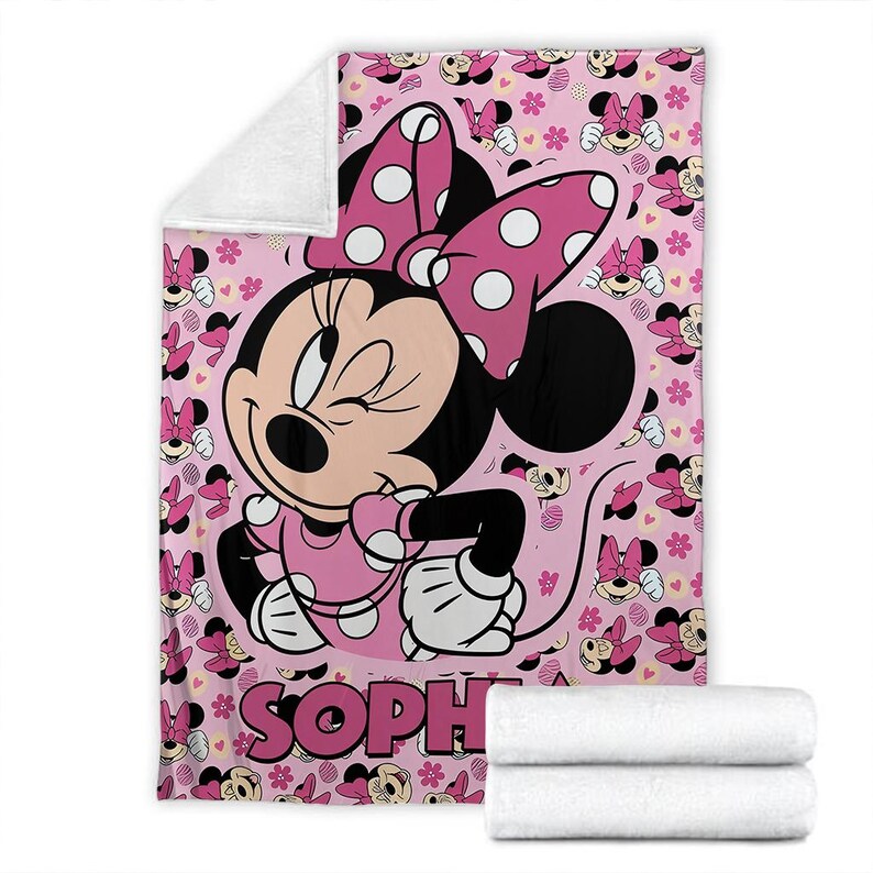 May include: Pink Minnie Mouse blanket featuring a large Minnie Mouse graphic and the name "SOPH" in pink. The blanket has a white fleece backing and is decorated with Minnie Mouse faces and bows.