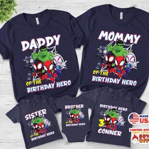 Puede incluir: Un conjunto de camisetas azul marino y un body de beb&eacute; con un gr&aacute;fico de superh&eacute;roes de Marvel que incluye a Hulk, Black Panther y Spider-Man. Las prendas muestran textos como DADDY, MOMMY, SISTER, BROTHER y BIRTHDAY HERO.
