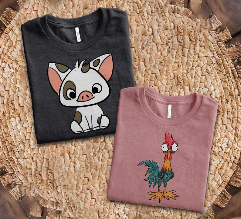 Puede incluir: Una camiseta gris oscuro con el gr&aacute;fico de un lech&oacute;n blanco con manchas marrones y orejas rosas, junto a una camiseta rosa polvoriento con el gr&aacute;fico de un gallo colorido con ojos grandes, cresta roja y plumas de cola verdes y azules.