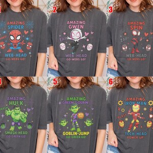 May include: A collection of six charcoal grey t-shirts featuring various cartoon character graphics. Each shirt displays a unique character, including Spider-Man, Gwen, Spin, Hulk, Green Goblin, and Iron Man, accompanied by themed text and icons.