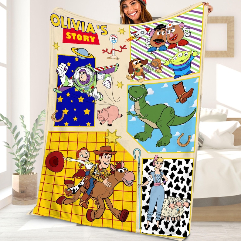 Puede incluir: Una manta colorida con personajes de la franquicia Toy Story. La manta es amarilla con un patr&oacute;n de cuadr&iacute;cula y presenta im&aacute;genes de Woody, Buzz Lightyear, Jessie, Rex y otros personajes. La manta tambi&eacute;n incluye el texto "Olivia's Story".