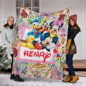 May include: A colorful Disney-themed blanket featuring Mickey Mouse, Minnie Mouse, Donald Duck, and Goofy. The blanket has a pink border with the name "HENRY" in red. The background is filled with various Disney characters.