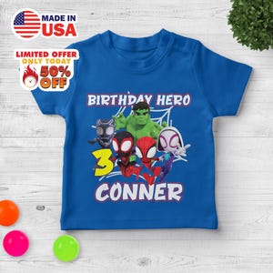 Puede incluir: Una camiseta azul real de manga corta con un estampado gr&aacute;fico de superh&eacute;roes de dibujos animados, incluyendo a Hulk, Black Panther, Spider-Man y Ghost-Spider. El texto dice BIRTHDAY HERO, el n&uacute;mero 3 en amarillo y el nombre CONNER en blanco.