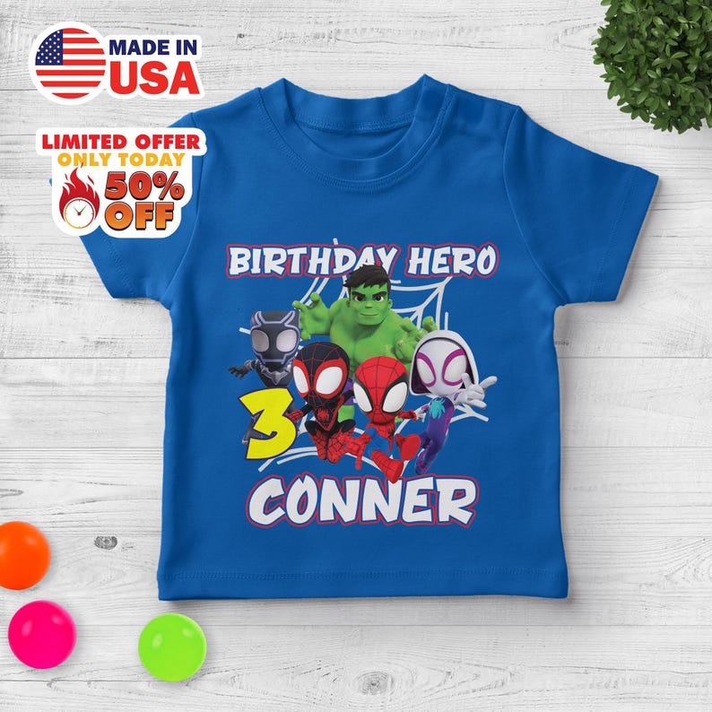 Puede incluir: Una camiseta azul real de manga corta con un estampado gr&aacute;fico de superh&eacute;roes de dibujos animados, incluyendo a Hulk, Black Panther, Spider-Man y Ghost-Spider. El texto dice BIRTHDAY HERO, el n&uacute;mero 3 en amarillo y el nombre CONNER en blanco.