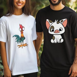 Puede incluir: Una camiseta blanca con un gallo de dibujos animados colorido de ojos grandes y una camiseta negra con un cerdito de dibujos animados de ojos grandes, orejas rosas y manchas marrones. Ambas camisetas tienen mangas cortas y cuello redondo.