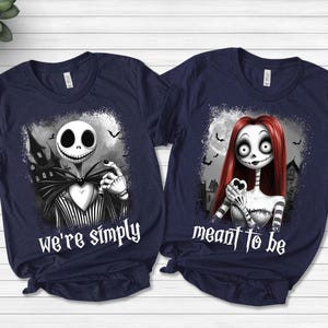 May include: Two navy blue short-sleeve t-shirts featuring graphic prints of characters from The Nightmare Before Christmas. The left shirt displays Jack Skellington with the text we're simply, and the right shirt displays Sally with meant to be.