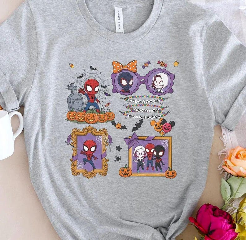 May include: A heather gray t-shirt featuring a Halloween-themed graphic with Spider-Man characters, pumpkins, a tombstone, and spiderwebs. The design includes text that reads SPIDEY AND AMAZING SPIDERMAN, surrounded by bats and decorative frames.