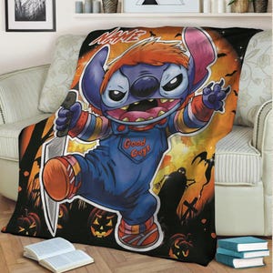 May include: A Halloween-themed throw blanket featuring a cartoon character dressed as Chucky, holding a knife. The blanket has a black background with orange accents, pumpkins, and bats. The character is wearing blue overalls with "Good Guys" printed on them.