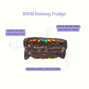 May include: M&M Galaxy Fudge cookie split in half, showing dark double chocolate cookie dough, hot fudge, and dark chocolate chips inside. The top is decorated with milk chocolate ganache and colorful mini M&M candies.