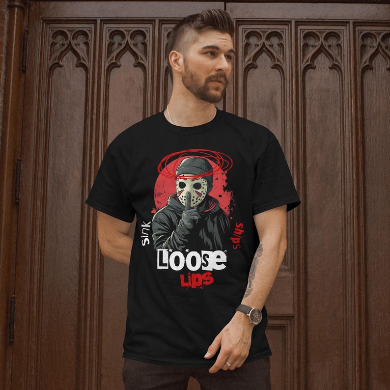 Op de afbeelding: Zwart T-shirt met een afbeelding van een gemaskerd figuur op een rode achtergrond en de tekst "Sink ships Loose Lips".