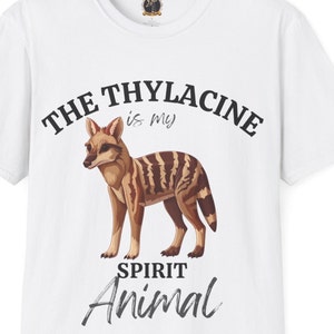 Op de afbeelding: Wit T-shirt met een zwarte grafische print van een buidelwolf, een buideldier, met de tekst "The Thylacine is my Spirit Animal".