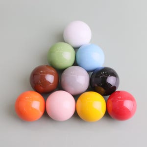 May include: Eleven glossy spheres in a range of colours: white, green, blue, brown, grey, black, orange, pink, yellow, and red. The spheres are arranged in a pyramid shape.