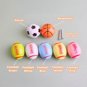 May include: A selection of sports-themed cabinet knobs. Features a football, basketball, and soccer ball, plus footballs in green, white, blue, yellow, and pink. Screws are included. The image text says "Basketball", "Soccer", "Football Green", "Football White", "Football Blue", "Football Yellow", "Football Pink".