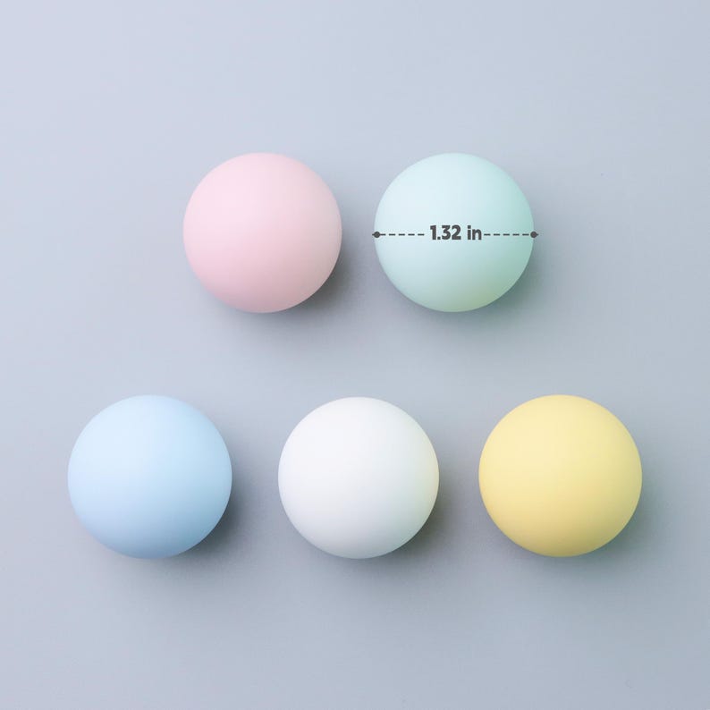 May include: Five pastel-colored spheres, each approximately 1.32 inches in diameter, are arranged on a gray surface. The spheres are in shades of pink, light green, blue, white, and yellow. The image is a top-down view.