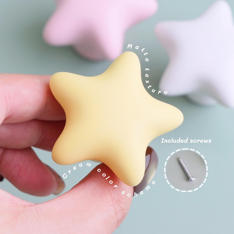 Op de afbeelding: Cr&egrave;mekleurige stervormige kastknop met een matte textuur. De afbeelding toont de knop in de hand van een persoon, met de tekst "Cr&egrave;me kleurenschema" en "Matte textuur". Schroeven zijn ook inbegrepen.