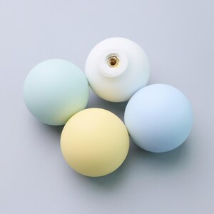 May include: A set of three ceramic mugs with a speckled, matte finish. Each mug features a different color: light blue, cream, and gray. The mugs have a simple, modern design and a comfortable handle.