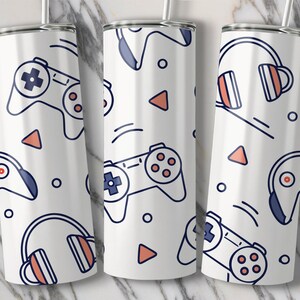 May include: White tumbler featuring a repeating pattern of blue and coral gaming controllers, headphones, triangles, and circles. The design is a line drawing style. The tumbler has a silver rim and a straw. The design creates a modern aesthetic.