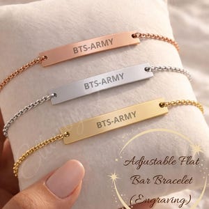 May include: Three adjustable flat bar bracelets in rose gold, silver, and gold, each engraved with "BTS-ARMY". The bracelets are displayed on a white pillow. The text "Adjustable Flat Bar Bracelet (Engraving)" is also visible.