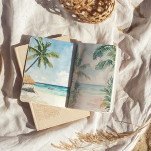 May include: An open sketchbook with watercolor paintings of tropical beaches. The left page shows a palm tree and a small boat on the water. The right page shows palm trees and a beach with a pink sky.