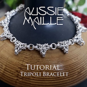 Könnte beinhalten: Ein silbernes Kettenhemdarmband mit einem dreieckigen Design. Das Armband liegt auf einer Holzoberfläche und der Text "TUTORIAL TRIPOLI BRACELET" befindet sich darunter.