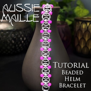May include: A silver beaded helm bracelet with pink beads. The bracelet is on a dark gray vase. The text "Tutorial Beaded Helm Bracelet" is on the right side of the image.