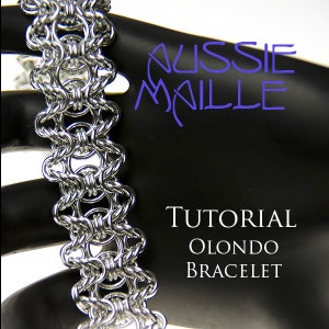 Op de afbeelding: Een zilveren kettingbaard armband met een geweven patroon, genaamd een Olondo armband, op een zwarte achtergrond met de tekst "Aussie Maille Tutorial Olondo Bracelet".