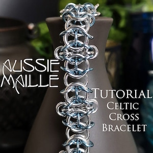 May include: A silver and blue Celtic cross bracelet made with chainmail. The bracelet is on a dark gray surface. The text "Aussie Maille Tutorial Celtic Cross Bracelet" is visible in the image.